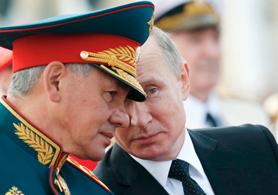 Russian President Vladimir Putin (R) speaks with Defense Minister Sergey Shoigu as they attend a ceremony for Russia’s Navy Day in Saint Petersburg on July 30. (Photo credit: Alexander Zemlianichenko/AFP/Getty Images)