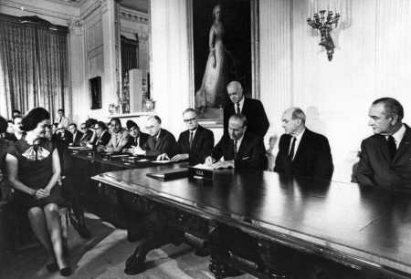 William Foster, chief U.S. negotiator on the NPT, director of the Arms Control and Disarmament Agency, and later Chair of the Arms Control Association Board, signs the NPT July 1, 1968, as President Lyndon Johnson and Lady Bird Johnson look on. U.S. Secretary of State Dean Rusk is seated next to the president, and a number of ambassadors are seated at the far end of the table, including Soviet Ambassador Anatoly Dobrynin (fifth from right among those seated). Photo courtesy of Larry Weiler